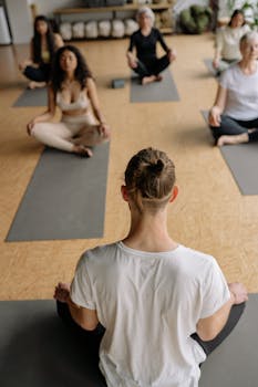 A diverse group of adults practicing yoga in an indoor studio setting, focusing on relaxation and wellness.