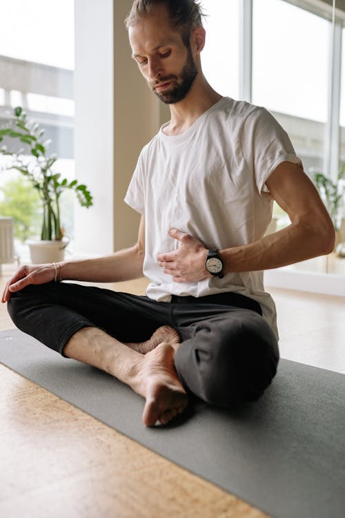 Free Man in White Shirt and Black Pants Sitting on Yoga Mat Stock Photo