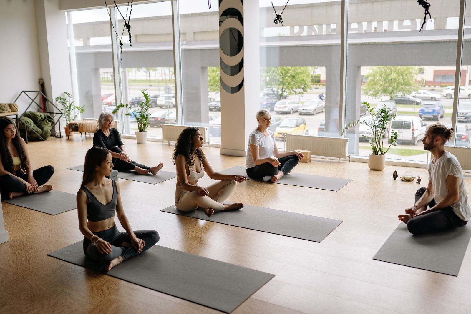 Group of students sitting cross-legged on yoga mats in a calm studio, practicing meditation to manage exam stress