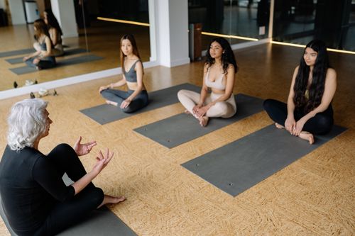 Free A yoga instructor guides three young women in a relaxing yoga session inside a studio. Stock Photo