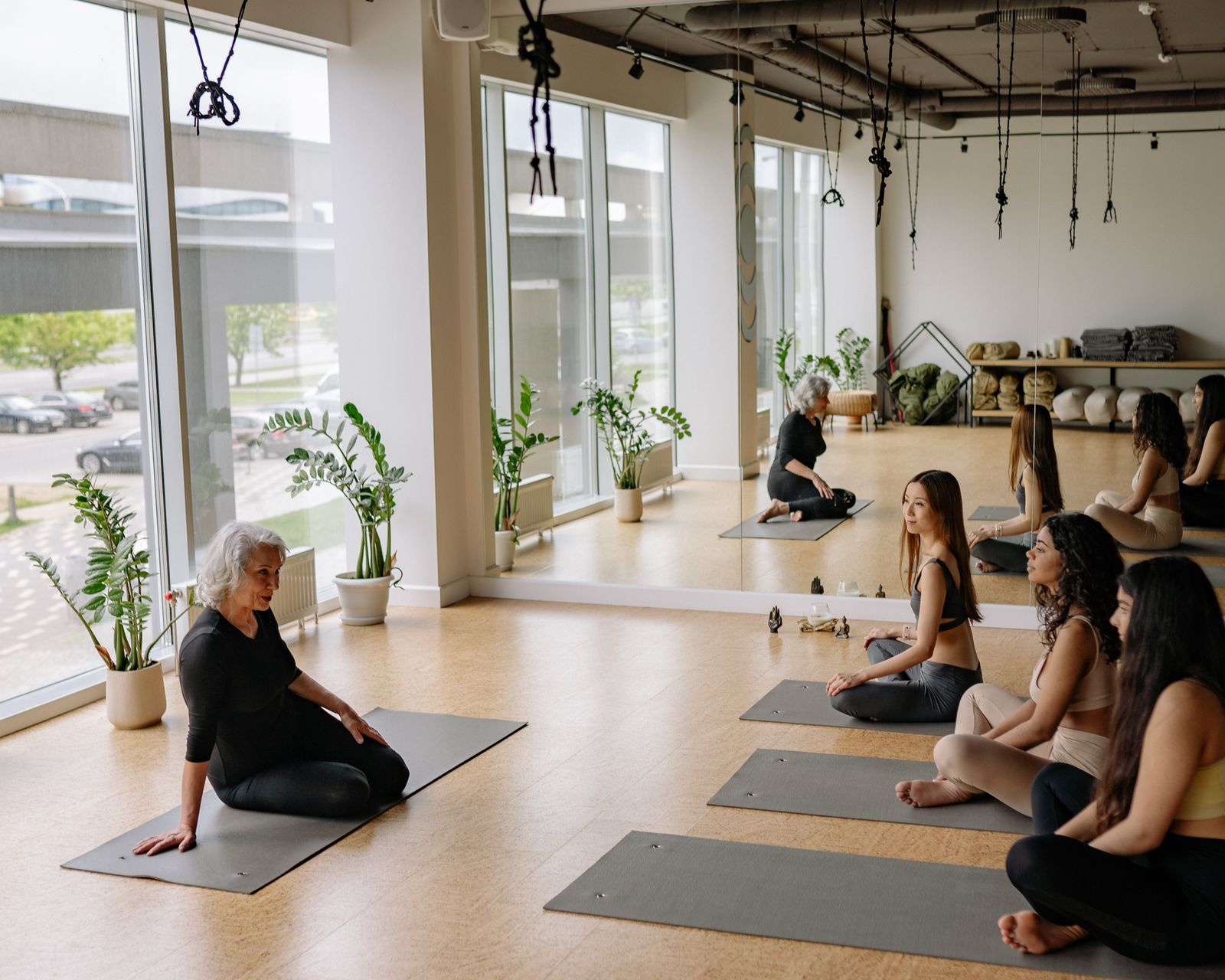 Yoga instructor guiding a diverse group of students through a class in a bright, plant-filled studio