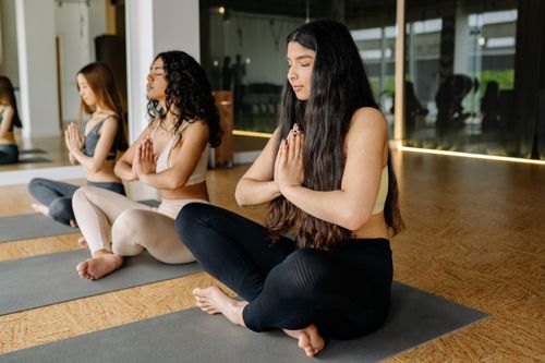 Free Group of diverse women practicing yoga indoors, focusing on meditation and relaxation. Stock Photo