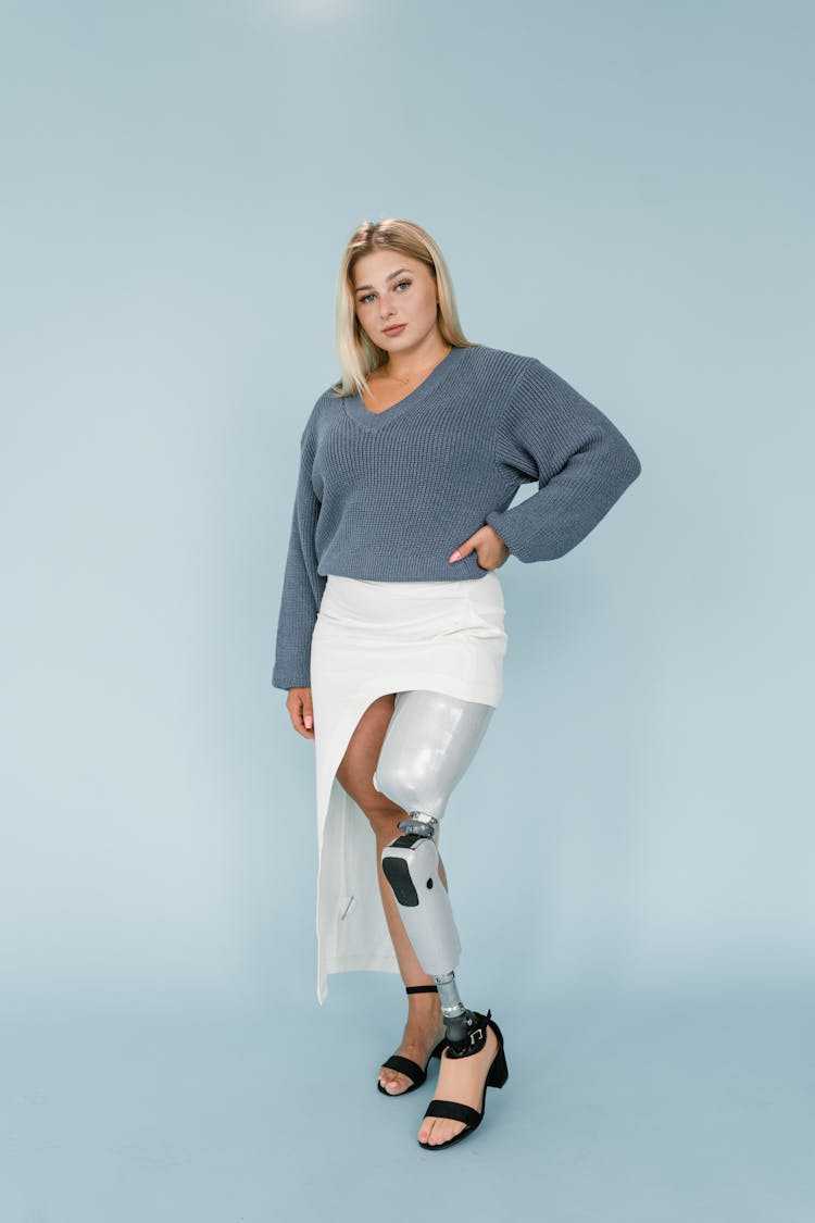 A Woman In Blue Sweater And White Skirt With Prosthetic Leg