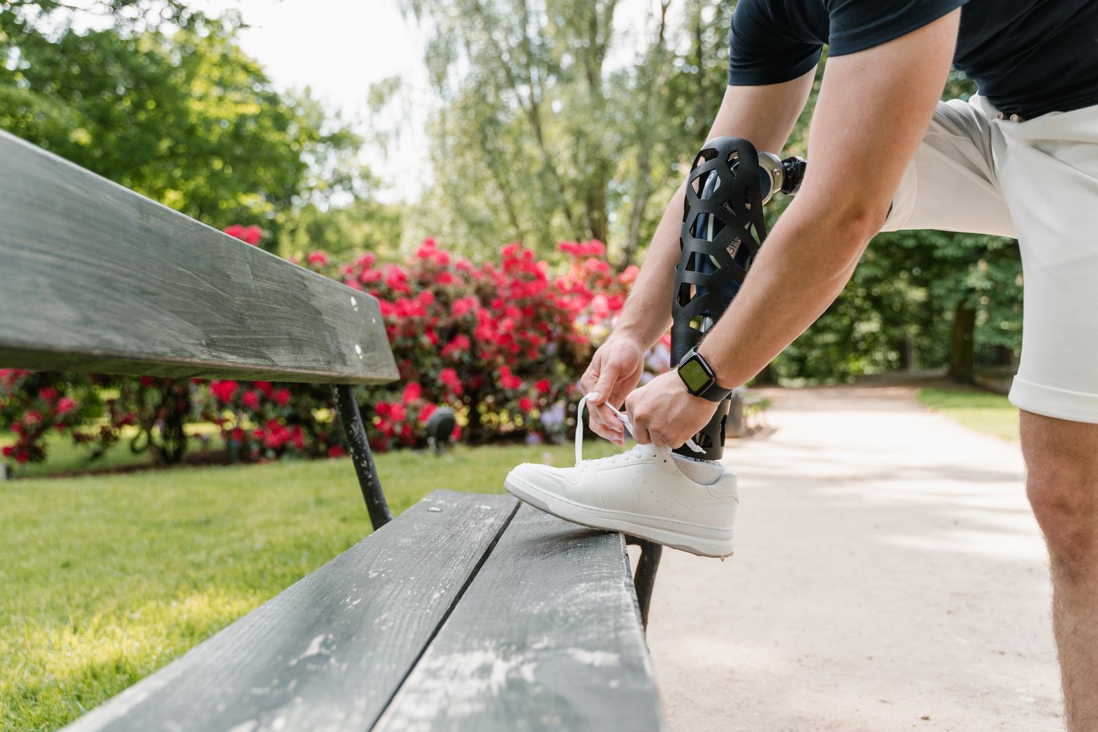 Runner tying shoes on a bright outdoor path before using knee support