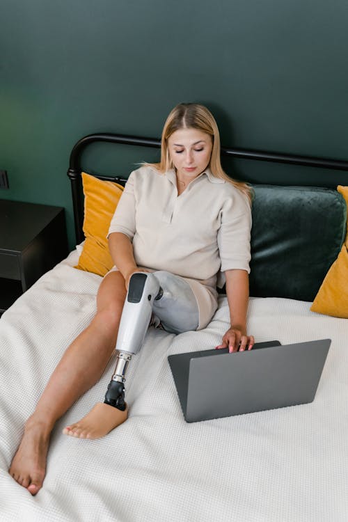 
A Woman with a Prosthetic Leg using a Laptop in Bed