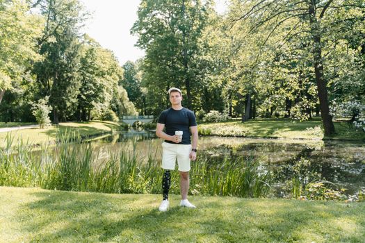 A man with a prosthetic leg enjoys a peaceful day in a lush park beside a pond.