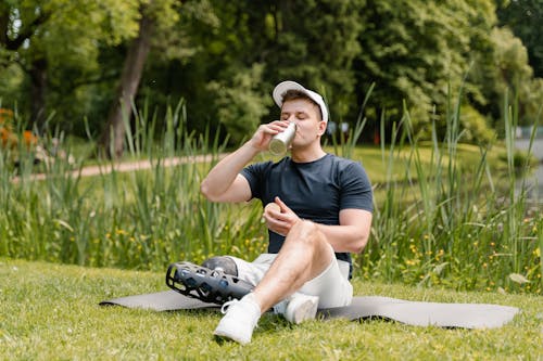 Man Sitting on Yoga Mat While Drinking from a Tumbler