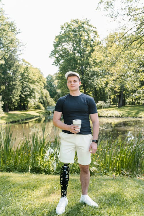 Man Standing on Grass While Holding a Cap