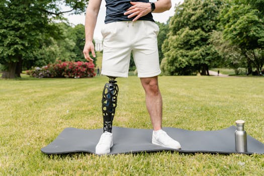 Close-up of a man with a prosthetic leg standing on a yoga mat outdoors.