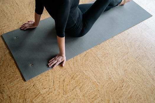 Woman in black clothing performing yoga pose on a mat indoors.