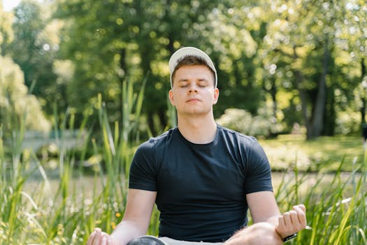 Man in black shirt meditates peacefully in a lush green park, eyes closed in relaxation