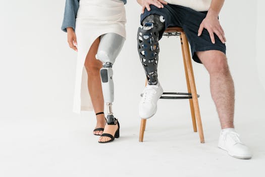 Two people with prosthetic legs sitting on stools, showcasing diversity and technology.