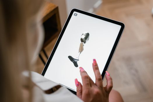 A woman interacts with a digital illustration of a prosthetic leg on a tablet screen.