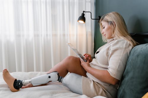 Woman sitting on Bed While Holding a Tablet