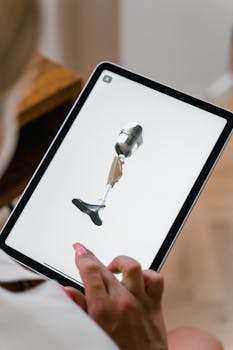Close-up of a woman holding a tablet displaying a prosthetic leg design indoors.