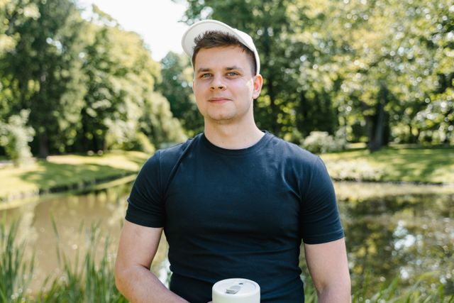 Young man in a cap standing by a park pond — photo by MART PRODUCTION on Pexels