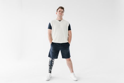 Portrait of a man with a prosthetic leg standing confidently in a bright studio setting.