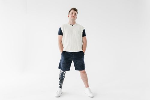 Free Portrait of a man with a prosthetic leg standing confidently in a bright studio setting. Stock Photo