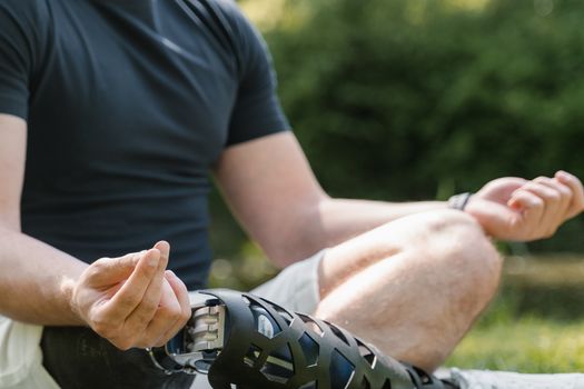 A person meditating in a park with a prosthetic leg, focusing on mindfulness and serenity.