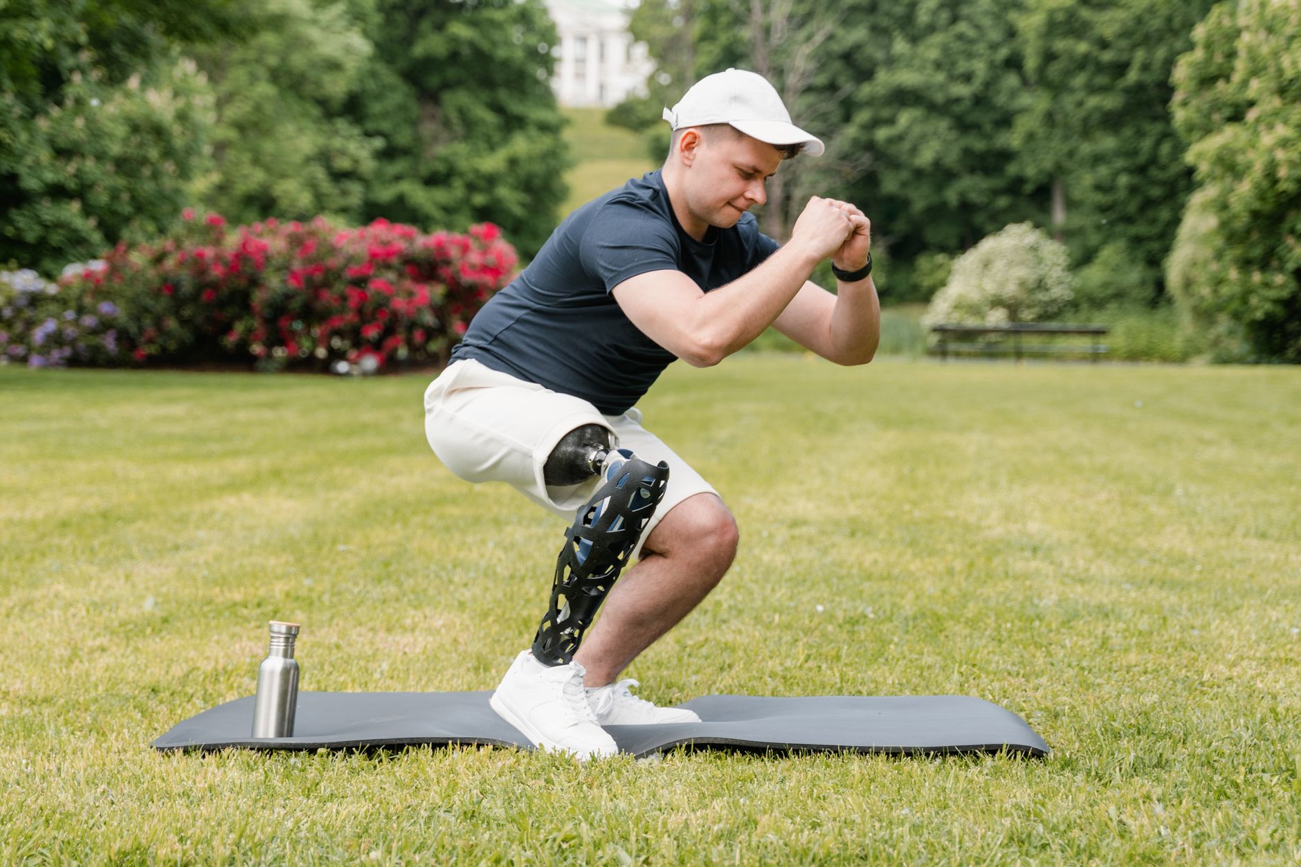 A man with a prosthetic leg exercises on a mat outdoors, promoting healthy lifestyle and fitness.