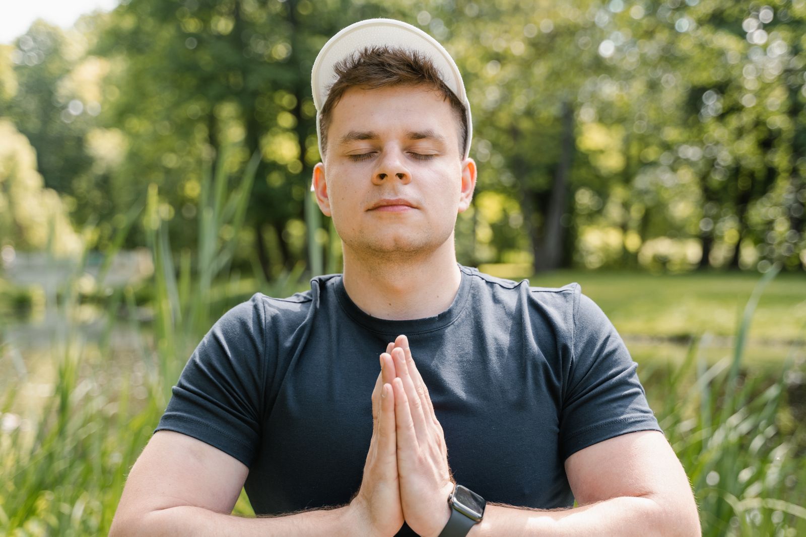Man sitting cross-legged and meditating outdoors in a park for mental clarity