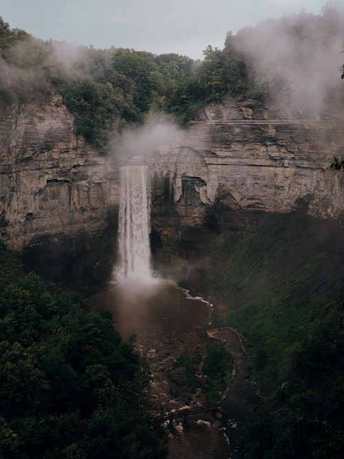 Free A breathtaking aerial shot of Taughannock Falls surrounded by lush greenery and mist. Stock Photo