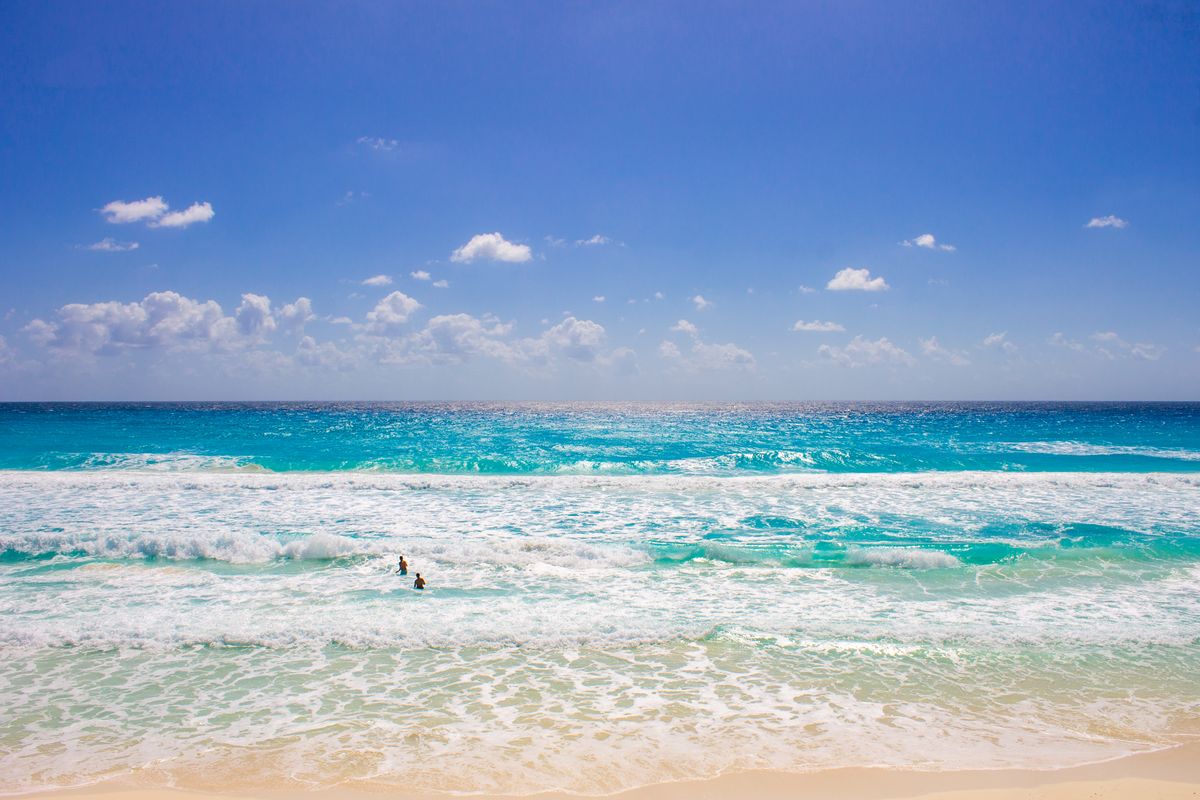 Escena vibrante de playa en Cancún con agua azul clara y cielos soleados.