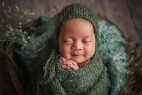 Close-Up Photo of a Cute Baby Wrapped in Green Knitted Fabric
