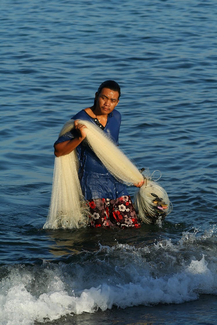 Man Walking Out Of The Sea With A Fishing Net 