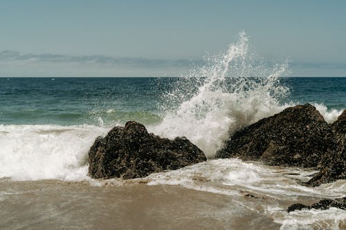 Free Ocean Waves Crashing on Brown Rock Formation Stock Photo