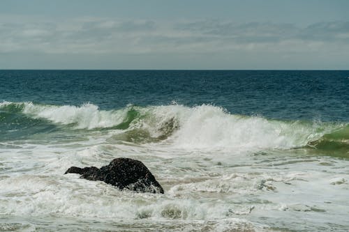 Free Black Rock Formation near Ocean Waves Stock Photo
