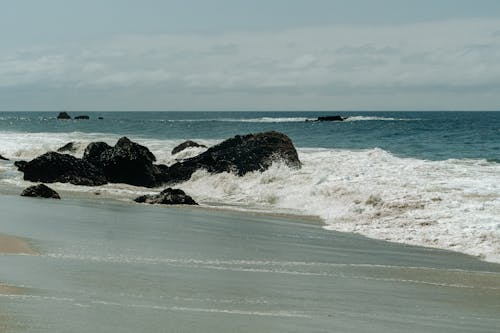 Foamy Water on Black Rock Formation near Seashore