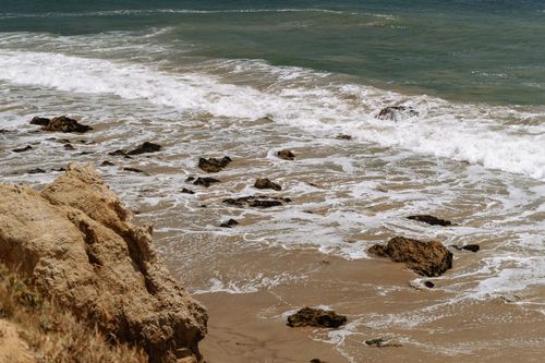Free Waves gently crashing against a rocky beach, creating a serene oceanic scene. Stock Photo