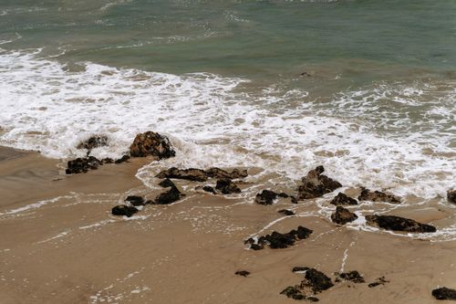 Free A peaceful beach scene with waves crashing on a rocky shore, perfect for nature themes. Stock Photo