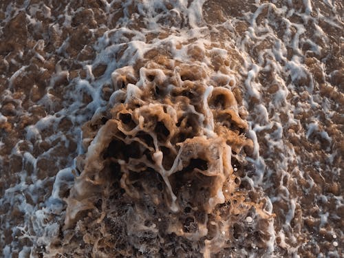 Close-up of Waves Mixed with Sand Splashing on the Shore 