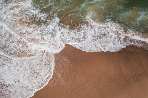 An Aerial Photography of Sea Waves Crashing on the Beach Sand