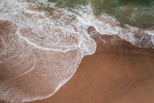 An Aerial Photography of Sea Foam on the Beach Sand