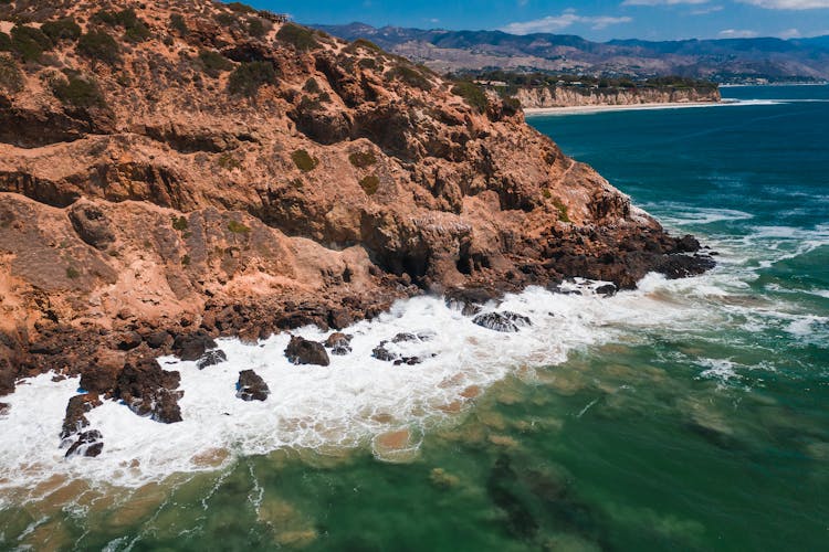 Waves Breaking On Rocky Cliffs On The Shore 