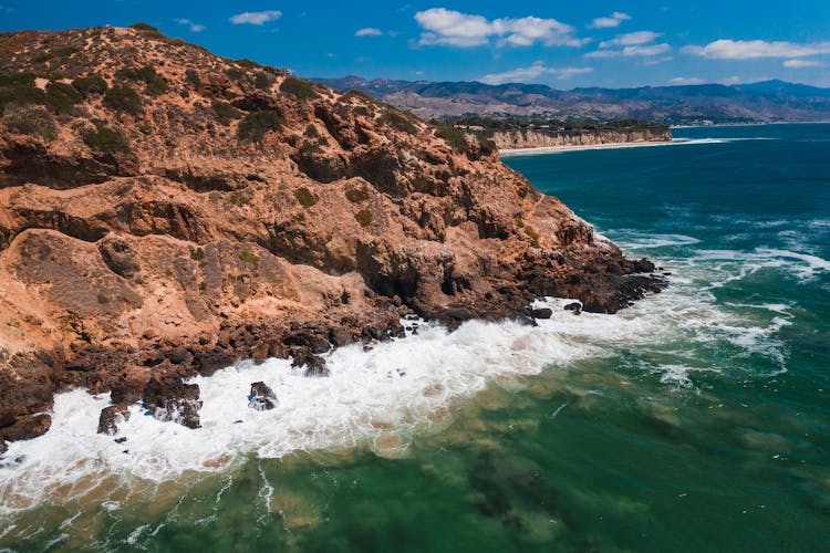 Waves Breaking On Rocky Cliffs On The Shore 