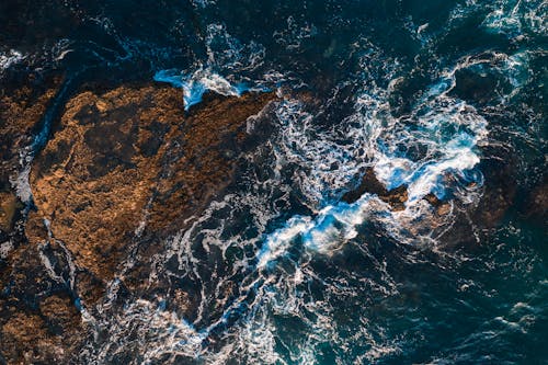 Bird's-eye View of Ocean Waves Crashing on Rocks