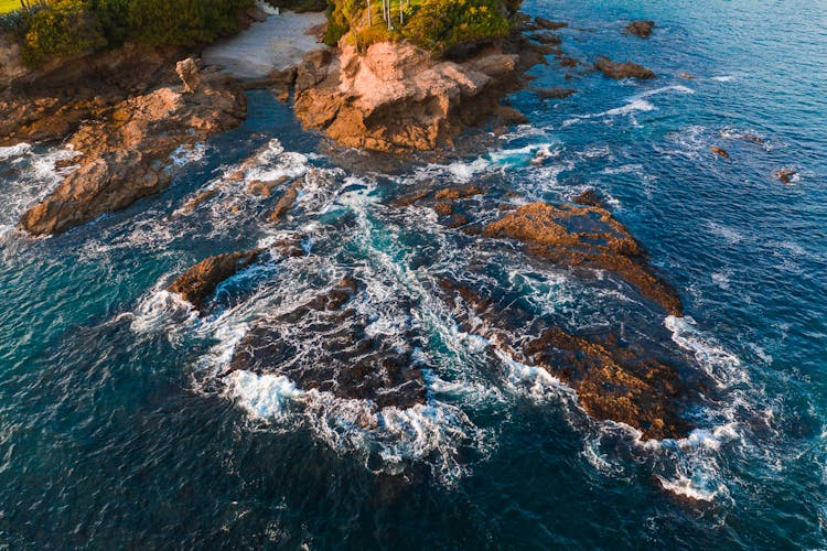 Ocean Waves Crashing On Brown Rocks