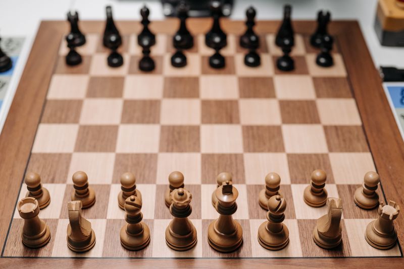 Overhead view of wooden chess pieces set up on a chessboard