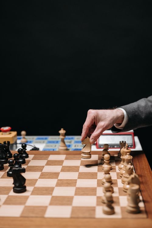 Free Close-up of a hand making a strategic move during a chess game with wooden pieces. Stock Photo