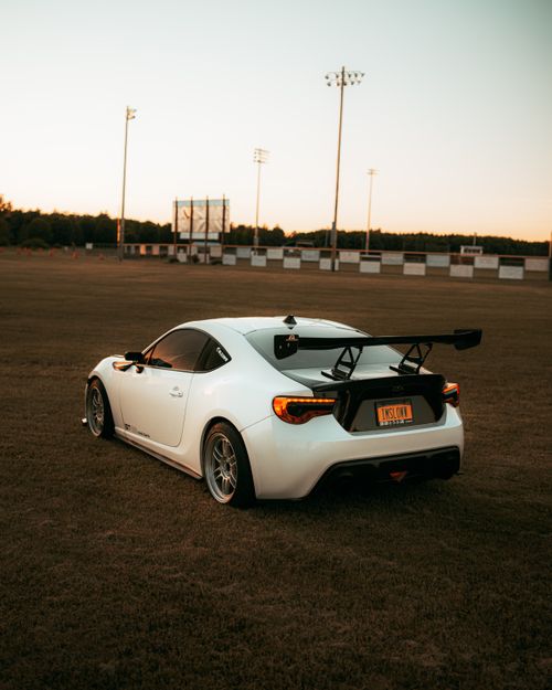 Free A sleek white sports car parked in a vast grassy field during sunset, creating a serene automotive scene. Stock Photo