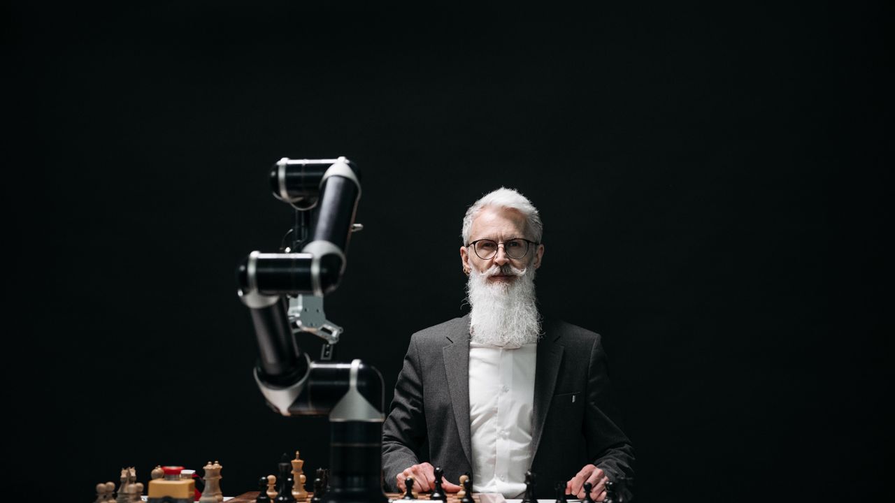 A bearded man in suit playing chess with robotic arm, showcasing AI strategy.