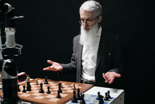 A senior man plays chess against a robot, mixing tradition with modern technology.