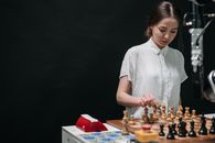 Woman in White Button Up Shirt Standing in Front of Chess Board Game