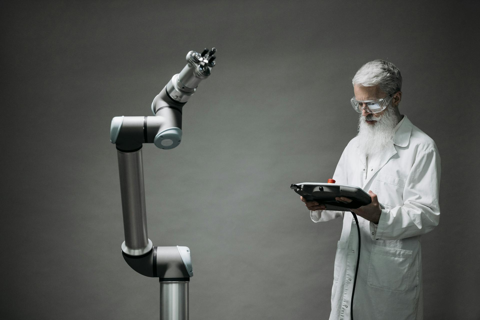 A scientist in a lab coat operates a high-tech robotic arm in a laboratory setting.