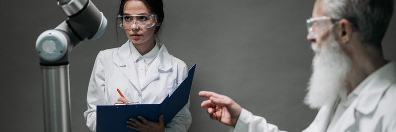 Scientists in lab coats analyze advanced robotics technology, highlighting innovation and teamwork.