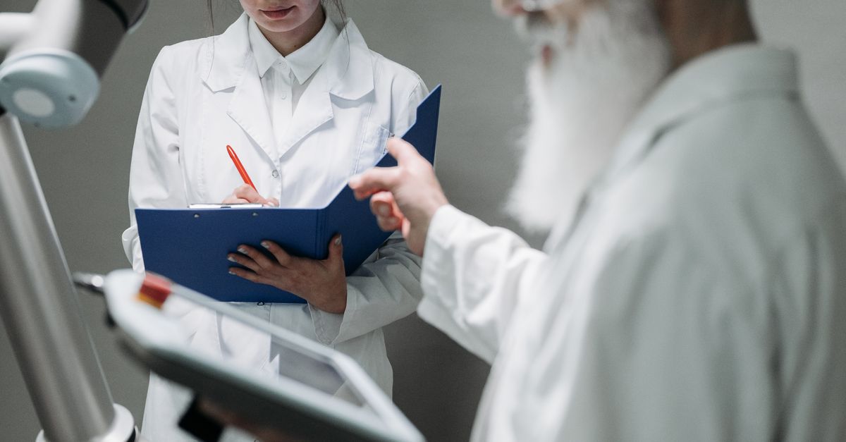 Photo by Pavel Danilyuk Researchers in lab coats interacting with advanced robotic arm technology.